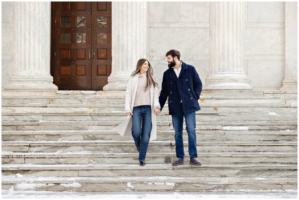 Winter engagement session at Princeton University with sparkling snow flurries and a couple in classic overcoats.